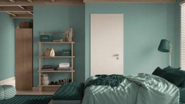 Cozy bedroom with teal colored walls and a white door